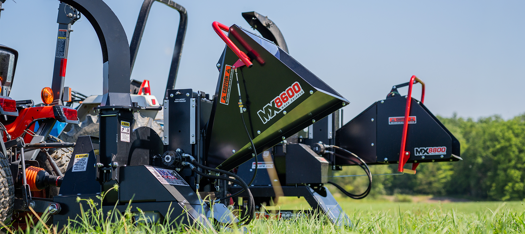 MX8600 wood chipper attached to tractor on grassy field, showcasing robust outdoor equipment.